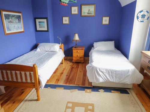 2 Betten in einem Schlafzimmer mit blauen Wänden und Holzböden in der Unterkunft The White House in Drumshanbo