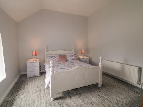 a bedroom with a white bed and two night stands at Mulroy Cottage in Glinsk