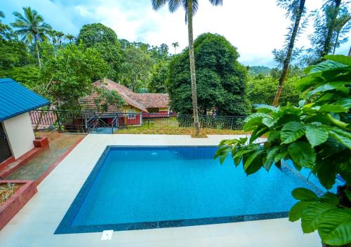 a pool in front of a house with trees at Chandragiri Wayanad Traditional Bungalow by VOYE HOMES in Vaduvanchal