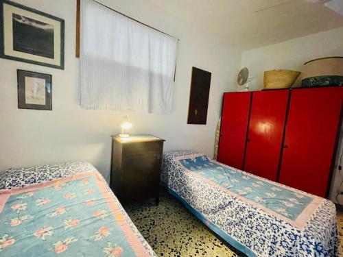 a bedroom with two beds and a red cabinet at Casa Racchia in Porto Santo Stefano