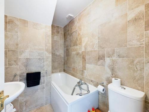 a bathroom with a tub and a toilet and a sink at Holiday Apartment Iris in Waterford