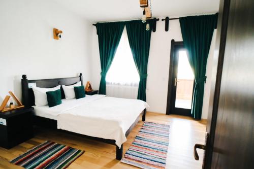 1 dormitorio con cama blanca y cortinas verdes en Pensiunea Tara Codrului, 