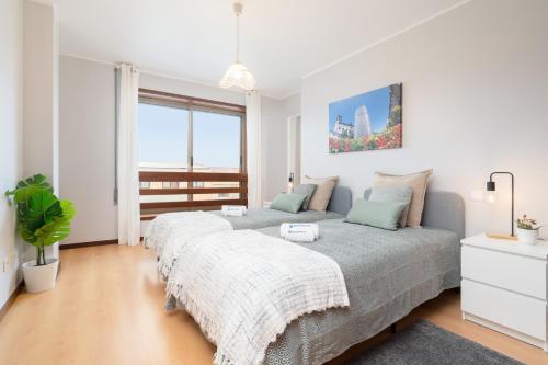 two beds in a white bedroom with a large window at Cozy Sunny Flat w/ Terrace - São João in Porto