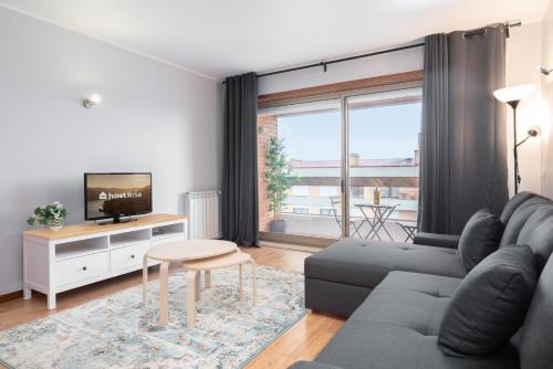 uma sala de estar com um sofá e uma televisão em Cozy Sunny Flat w/ Terrace - São João no Porto