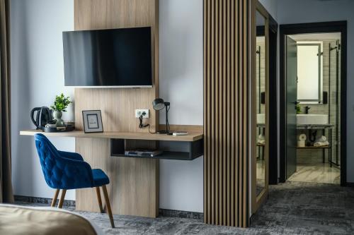 a bedroom with a desk with a tv and a blue chair at GBU Home Timisoara in Timişoara