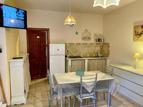 a kitchen with a table with chairs and a refrigerator at Appartamento L'Oleandro in Capoliveri