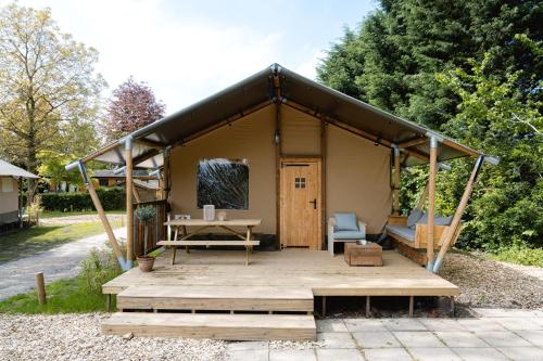a tent with a table and a chair on a wooden deck at Recreatiepark de Markplas in Opheusden