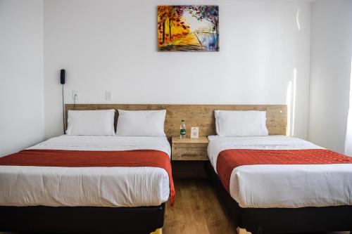duas camas num quarto de hotel com uma fotografia na parede em Nogal Suite Hotel Ipiales em Ipiales