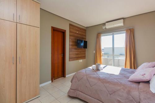 a bedroom with a bed and a television and a window at Hotel Morada Del Este in Canoas