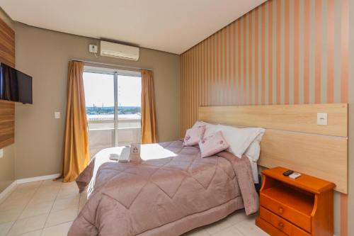 a bedroom with a large bed and a window at Hotel Morada Del Este in Canoas