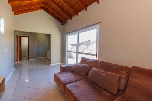 a living room with a brown couch and a large window at Hotel Morada Del Este in Canoas