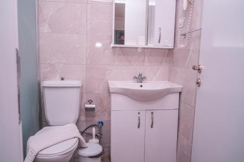 une salle de bain avec des toilettes blanches et un lavabo dans l'établissement ÖZCEM APART HOTEL FETHİYE, à Fethiye