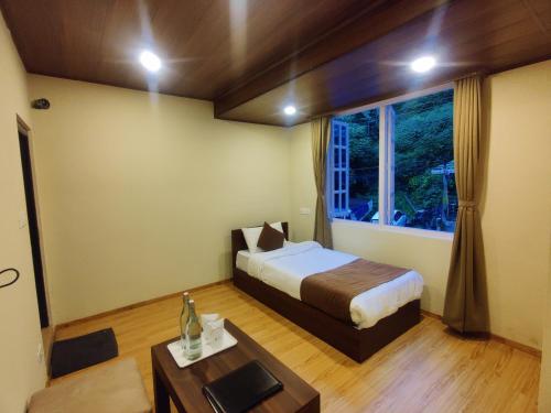 a bedroom with a bed and a table and a window at Keswani Group Tashi Heritage Hotel & Resort in Gangtok