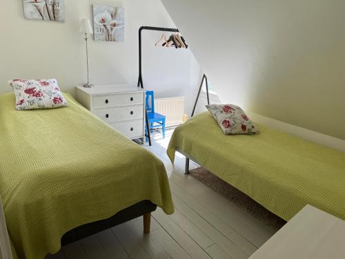 a bedroom with two beds and a dresser at Villa Brigitta, havsnära boende mittemot Klostret i Ystad centrum in Ystad