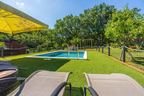 a swimming pool with two chairs and an umbrella at PLAVAC in Kostelj