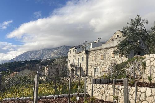 a large stone building on a hill with a fence at House Mate in Podgora