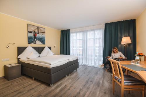a woman sitting in a hotel room with a bed at Hotel am Park in Hückelhoven