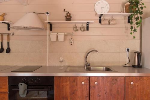 eine Küche mit einem Waschbecken und einer Uhr an der Wand in der Unterkunft metaxaki cottage in Mikros Gialos