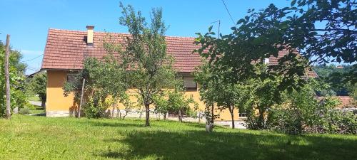 a yellow house with a red roof and some trees at Pri Fiškušu in Duga Resa