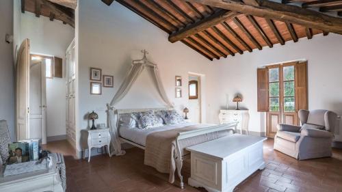 a bedroom with a white bed and a chair at Villa Fraiano in Palaia