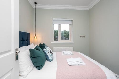 a white bedroom with a bed with green pillows at 5 Star - The Ulsterville Residences - Free On-site Parking in Belfast