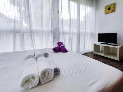 1 dormitorio con 1 cama blanca con toallas y TV en Apartamento loft en Castelldefels junto la playa, en Castelldefels