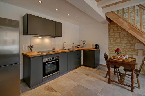 La cuisine est équipée de placards noirs, d'une table et d'un réfrigérateur. dans l'établissement La Maronniere, à Challignac