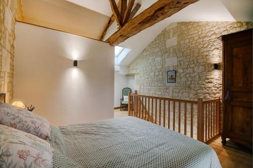 1 dormitorio con cama y pared de piedra en La Maronniere, en Challignac