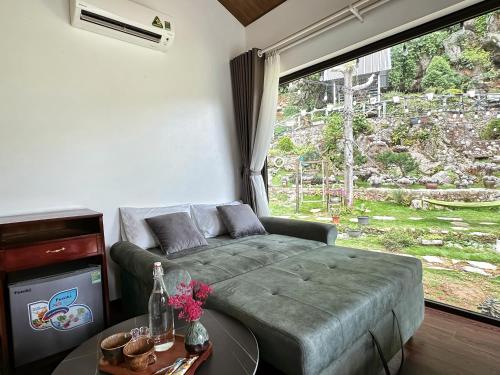 a living room with a couch and a large window at Gobies Garden in Mộc Châu