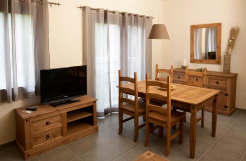 a dining room with a wooden table and a television at Apartaments Rural Montseny in gualba de Dalt