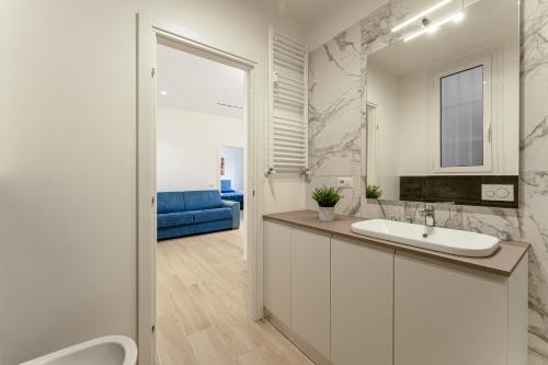 a white bathroom with a sink and a blue couch at Piazza Pio Suite Home in Rome