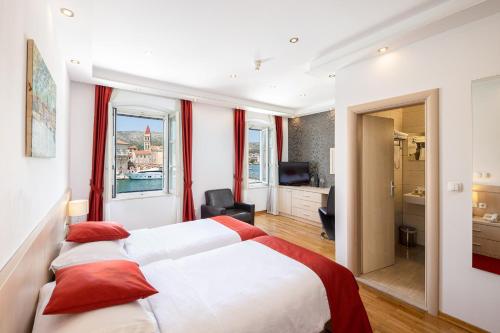 ein Hotelzimmer mit einem großen Bett mit roten Kissen in der Unterkunft Heritage Hotel Vila Sikaa in Trogir