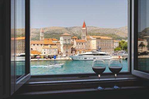two glasses of wine sitting in front of a window at Heritage Hotel Vila Sikaa in Trogir