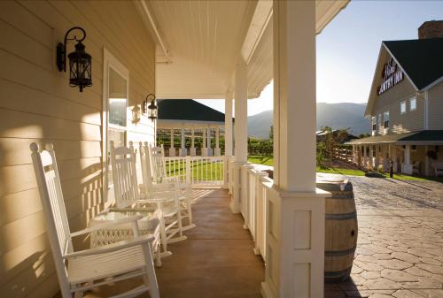a porch of a white house with chairs and a barrel at Wine Country Inn in Palisade