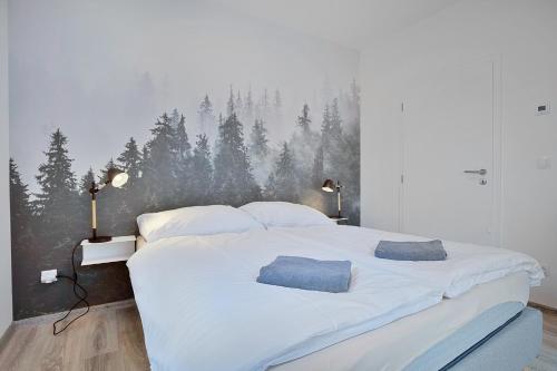a bedroom with a large white bed with a forest mural on the wall at Mirabel Apartments Klinovec in Loučná pod Klínovcem