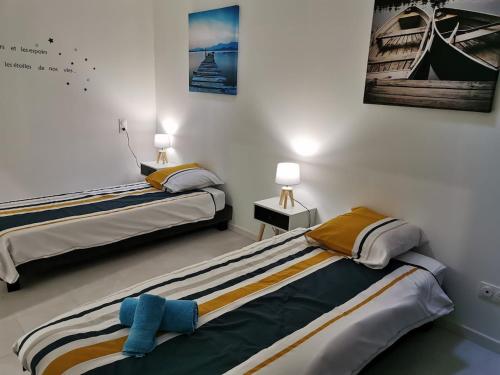 サン・ローラン・ド・ラ・サランクにあるJolie maison de vacancesのランプ2つが備わる客室で、ベッド2台が備わります。