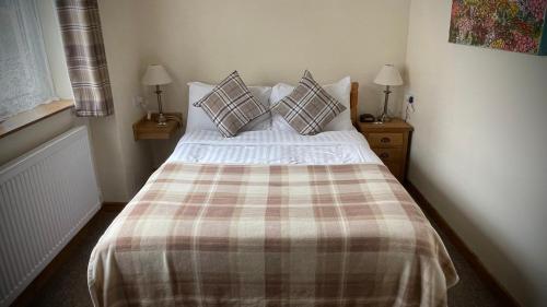 a bedroom with a bed with a plaid blanket and pillows at The White Horse Inn, Clun in Clun