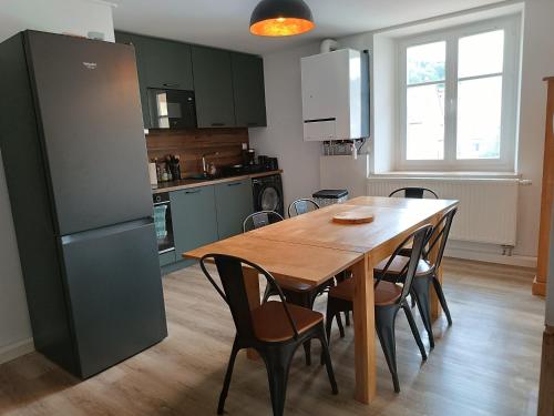 une cuisine avec une table en bois avec des chaises et un réfrigérateur dans l'établissement Le Nesdel, à Gérardmer