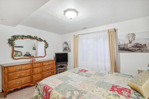 a bedroom with a bed and a dresser and a mirror at Cozy American Fork Retreat with Electric Fireplace in American Fork