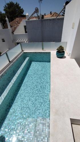 a swimming pool with blue tiles on the side of a building at Casa da Torre - A Gema Escondida de Tavira in Tavira