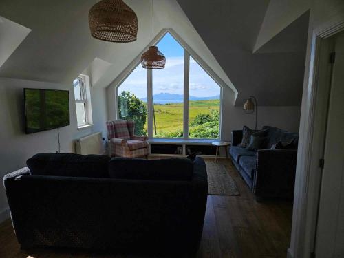 a living room with two couches and a large window at Hillside House in Elgol