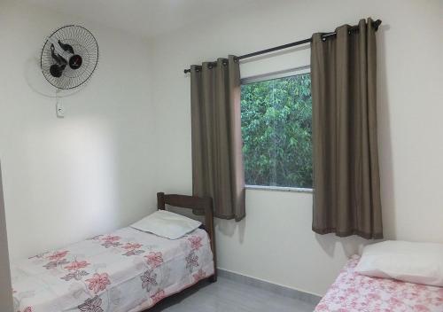 1 dormitorio con 2 camas y ventana con ventilador en Residencial Recanto da Lagoa - Praia de Taperapuan, en Porto Seguro
