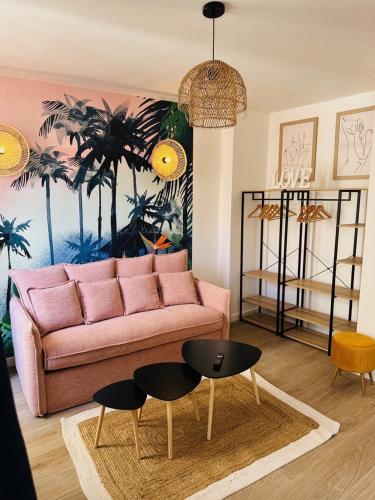 - un salon avec un canapé rose et 2 tables dans l'établissement Les Appartements de Nana 8 - Studio hypercentre, Rue Meynadier, Palais & Plage, clim, wifi, à Cannes