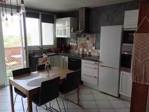 een keuken met een tafel en een witte koelkast bij Appart' cosy climatisé à 10' des plages et de Sète in Frontignan