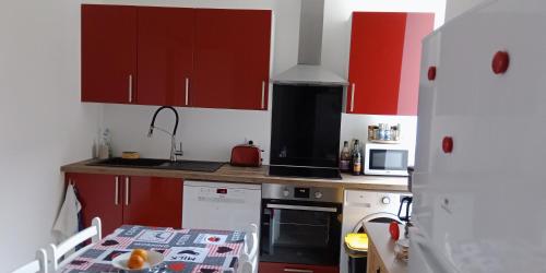 una pequeña cocina con armarios rojos y una mesa. en L'Isard, en Pierrefitte-Nestalas