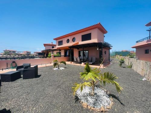 a house with a patio with palm trees in front of it at Casa Alaia in Lajares