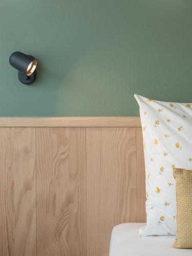 a lamp on a wall next to a bed with a pillow at Dianthus Apartment in Lana