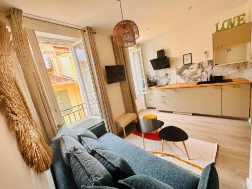 un salon avec un canapé bleu et une cuisine dans l'établissement Les Appartements de Nana 6 - Studio hypercentre, Rue Meynadier, Palais & Plage, clim, wifi, à Cannes
