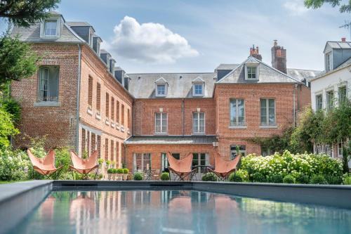 une cour avec une piscine en face d'un bâtiment dans l'établissement les Myrrhophores et Spa, Chambres d'Hôtes et Gîtes de charme, à Abbeville