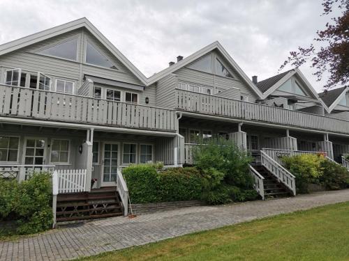 uma grande casa branca com um alpendre e escadas em Bergland apartment 23 - close to the center of Kragerø em Kragerø